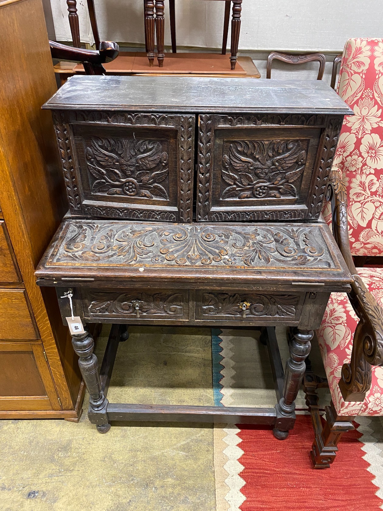 A 1920's Jacobean Revival carved oak writing table, width 76cm, depth 50cm, height 109cm